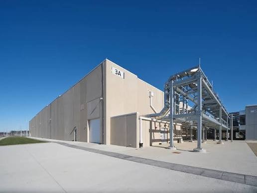 Exterior of a hyperscale data center building with adjacent electrical and mechanical infrastructure, illustrating mission-critical facility design and high-capacity power distribution systems.